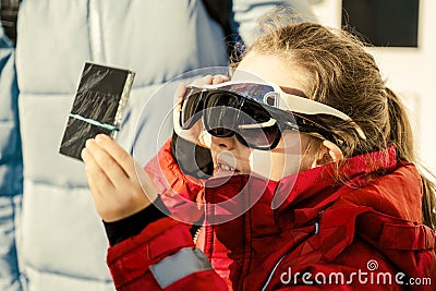 Kid watching solar eclipse with glass dark filter and several sunglasses Stock Photo