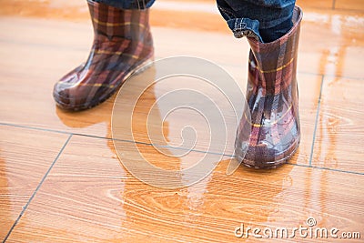 Kid wearing waterproof gumboots standing on wet floor Stock Photo