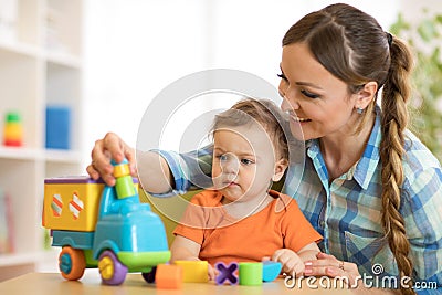 Kid and woman playing with developmental toy in daycare or kindergarten Stock Photo