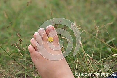 Kids bare feet with yellow flower on the grass Stock Photo