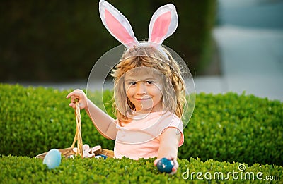 Kids boy hunting easter eggs. Easter kids boy in bunny ears hunting easter eggs outdoor. Cute child in rabbit costume Stock Photo