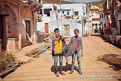 Kids carry a heavy bag on a dusty indian street Editorial Stock Photo