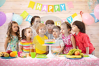 Kids celebrate birthday party and blow candles on festive cake Stock Photo