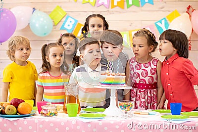 Kids celebrate birthday party and blow candles on festive cake Stock Photo