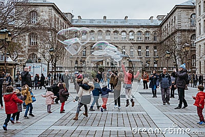 Kids chasing giant soap bubbles on a street in Paris, France Editorial Stock Photo