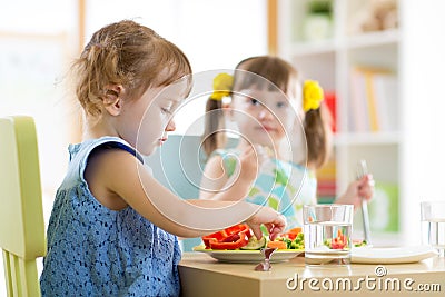 Kids children eating vegetables in kindergarten or at home Stock Photo