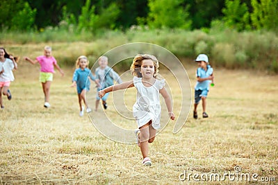 Kids, children running on meadow in summer`s sunlight Stock Photo