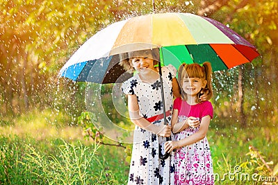 Kids with colorful umbrella playing in autumn shower rain. Little girls play in park by rainy weather. Stock Photo