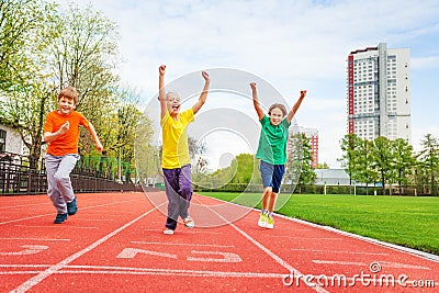 Kids in colorful uniforms with arms up running Stock Photo