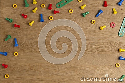 Kids construction toys tools border. Colorful screws and nuts on wooden background. Top view. Flat lay Stock Photo