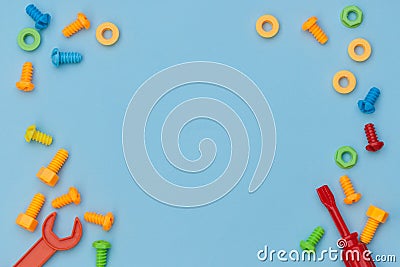 Kids construction toys tools: colorful screwdrivers, screws and nuts on blue background. Top view. Flat lay. Copy space for text Stock Photo