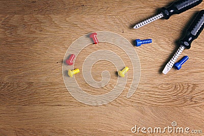 Kids construction toys tools: colorful screwdrivers, screws and nuts on wooden background. Top view. Flat lay. Copy Stock Photo