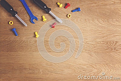 Kids construction toys tools: colorful screwdrivers, screws and nuts on wooden background. Top view. Flat lay. Copy Stock Photo