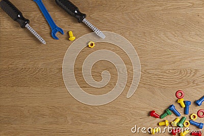 Kids construction toys tools: colorful screwdrivers, screws and nuts on wooden background. Top view. Flat lay. Copy Stock Photo