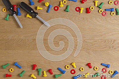 Kids construction toys tools: colorful screwdrivers, screws and nuts on wooden background. Top view. Flat lay. Copy Stock Photo