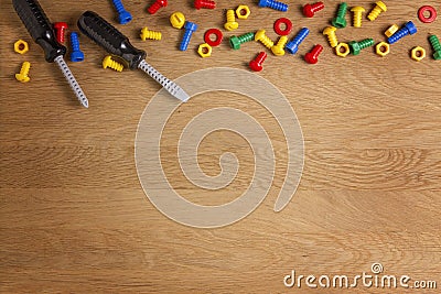 Kids construction toys tools: colorful screwdrivers, screws and nuts on wooden background. Top view. Flat lay. Copy Stock Photo