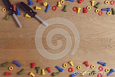 Kids construction toys tools: colorful screwdrivers, screws and nuts on wooden background. Top view. Flat lay. Copy Stock Photo