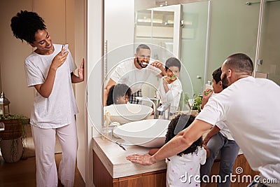 Kids and dad brushing teeth in bathroom, reflection in mirror and mom with phone taking picture at bedtime. Love, happy Stock Photo