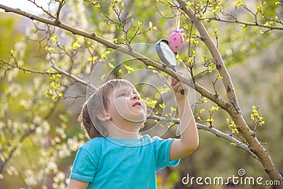 Kids on Easter egg hunt in blooming spring garden. Children searching for colorful eggs in flower meadow. Toddler boy and his brot Stock Photo