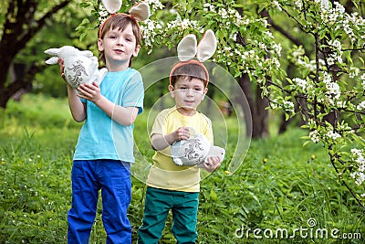 Kids on Easter egg hunt in blooming spring garden. Children searching for colorful eggs in flower meadow. Toddler boy and his brot Stock Photo