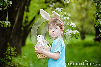 Kids on Easter egg hunt in blooming spring garden. Children searching for colorful eggs in flower meadow. Toddler boy and his brot Stock Photo