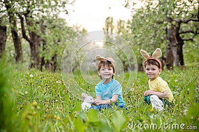 Kids on Easter egg hunt in blooming spring garden. Children searching for colorful eggs in flower meadow. Toddler boy and his brot Stock Photo