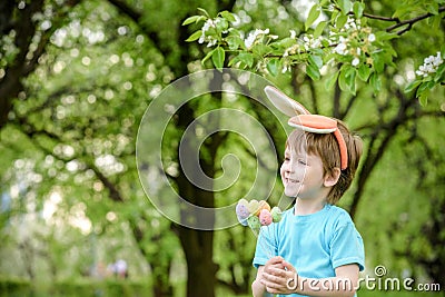 Kids on Easter egg hunt in blooming spring garden. Children searching for colorful eggs in flower meadow. Toddler boy and his brot Stock Photo