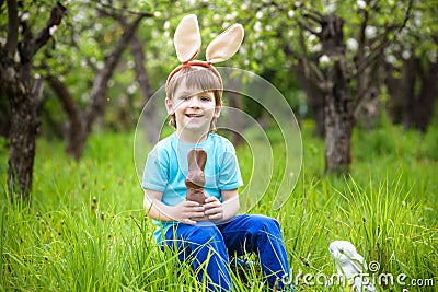 Kids on Easter egg hunt in blooming spring garden. Children searching for colorful eggs in flower meadow. Toddler boy and his brot Stock Photo