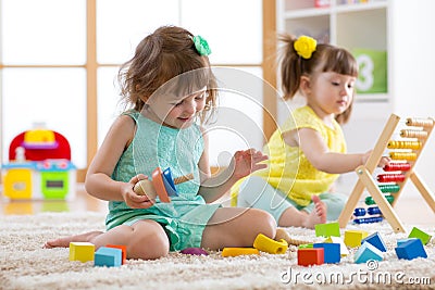 Kids are engaging in daycare. Two toddler children playing with educational toys in kindergarten. Stock Photo