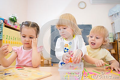Kids group playing puzzle and other board games in kindergarten Stock Photo