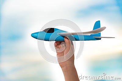 Kids hand lifting up a blue airplane model Stock Photo