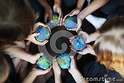 Kids hands holding cupping globe balls together Stock Photo
