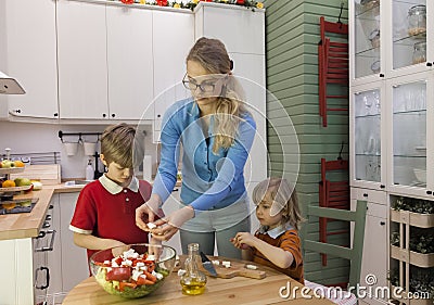 Kids helping mother preparing vegetable salad. Stock Photo