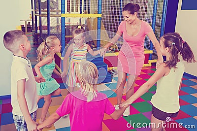 Kids holding each others hands and dancing with teacher Stock Photo