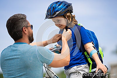 Kids insurance. Father and son concept. Father teaching son riding bike. Father helping his son to wear a cycling helmet Stock Photo