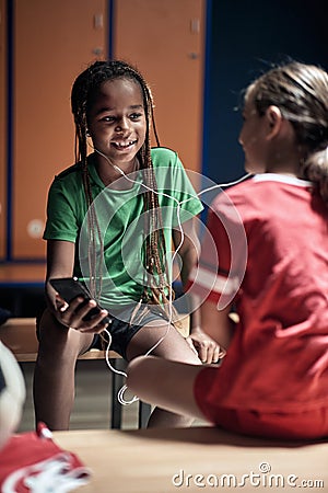 Kids listening to the music on smartphone before training. Children team sport Stock Photo