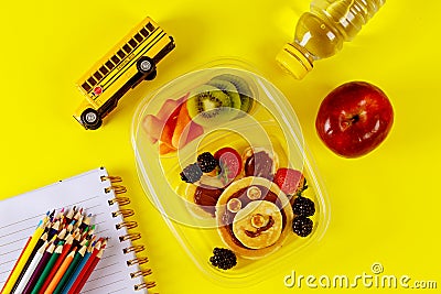 Kids lunch box with pancake, berries and apple on yellow background Stock Photo