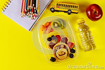 Kids lunch box with pancake, berries, drink and apple on yellow background Stock Photo