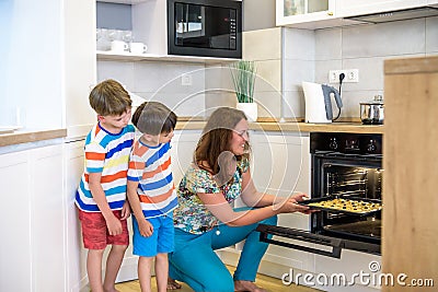 Kids and mother baking. Two children and parent cooking. Little boy and brother boy cook and bake in a white kitchen with modern Stock Photo