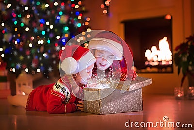 Kids opening Christmas presents at fireplace Stock Photo