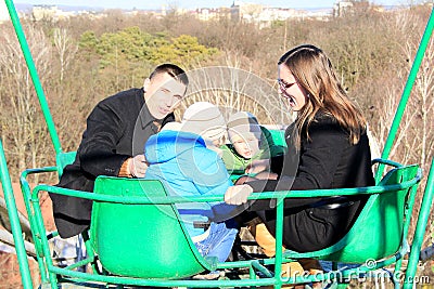 Kids with parents on a viewing car in an amusement park in the early spring Stock Photo