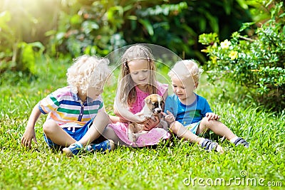 Kids play with puppy. Children and dog in garden. Stock Photo