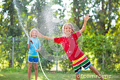 Kids play with water sprinkle hose. Summer garden Stock Photo