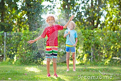 Kids play with water sprinkle hose. Summer garden Stock Photo