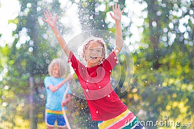 Kids play with water sprinkle hose. Summer garden Stock Photo