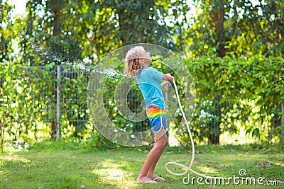 Kids play with water sprinkle hose. Summer garden Stock Photo