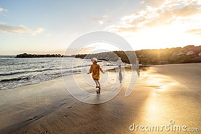 Kids playing on the beach. Little boy and girls running at sea shore at sunset. Family summer vacation vibes Stock Photo