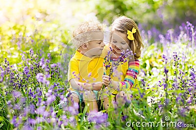 Kids playing in blooming garden with bluebell flowers Stock Photo