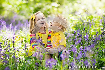 Kids playing in blooming garden with bluebell flowers Stock Photo