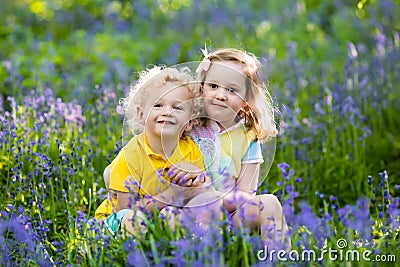Kids playing in blooming garden with bluebell flowers Stock Photo